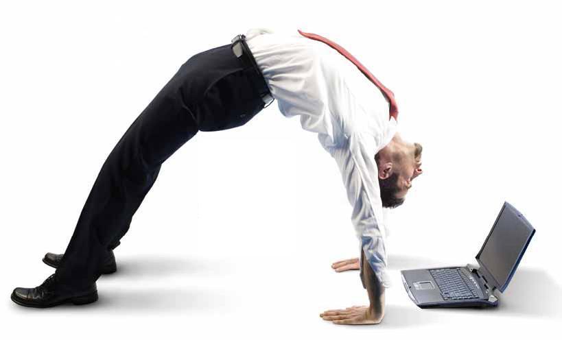 Business man bending over backwards while looking at his computer.